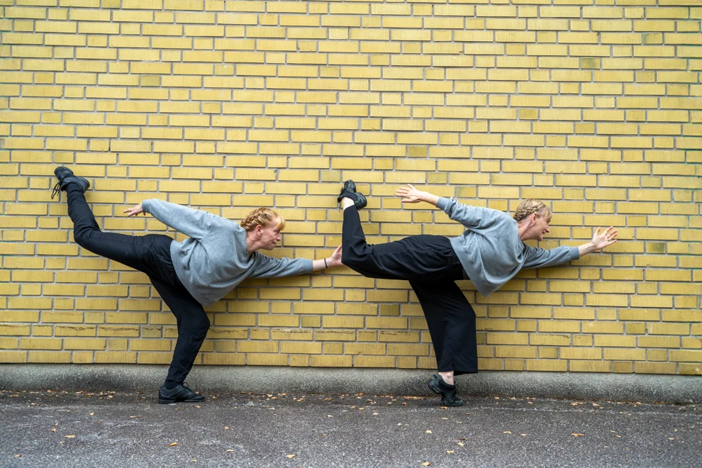 Två dansare vid en tegelvägg